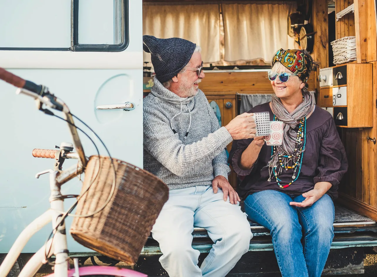 man en vrouw drinken thee in camperdeur