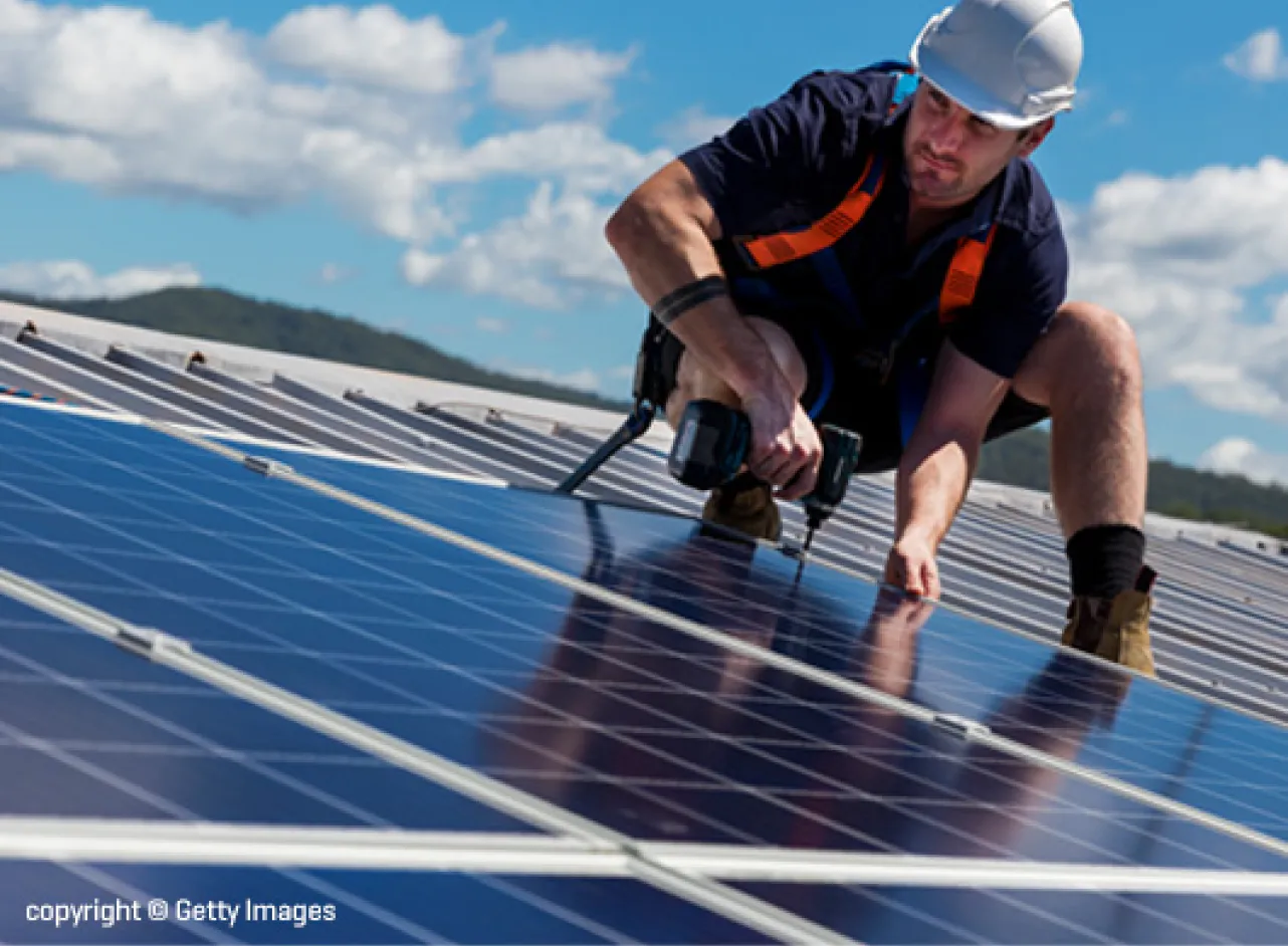 Un homme se tient sur le toit près de panneaux solaires